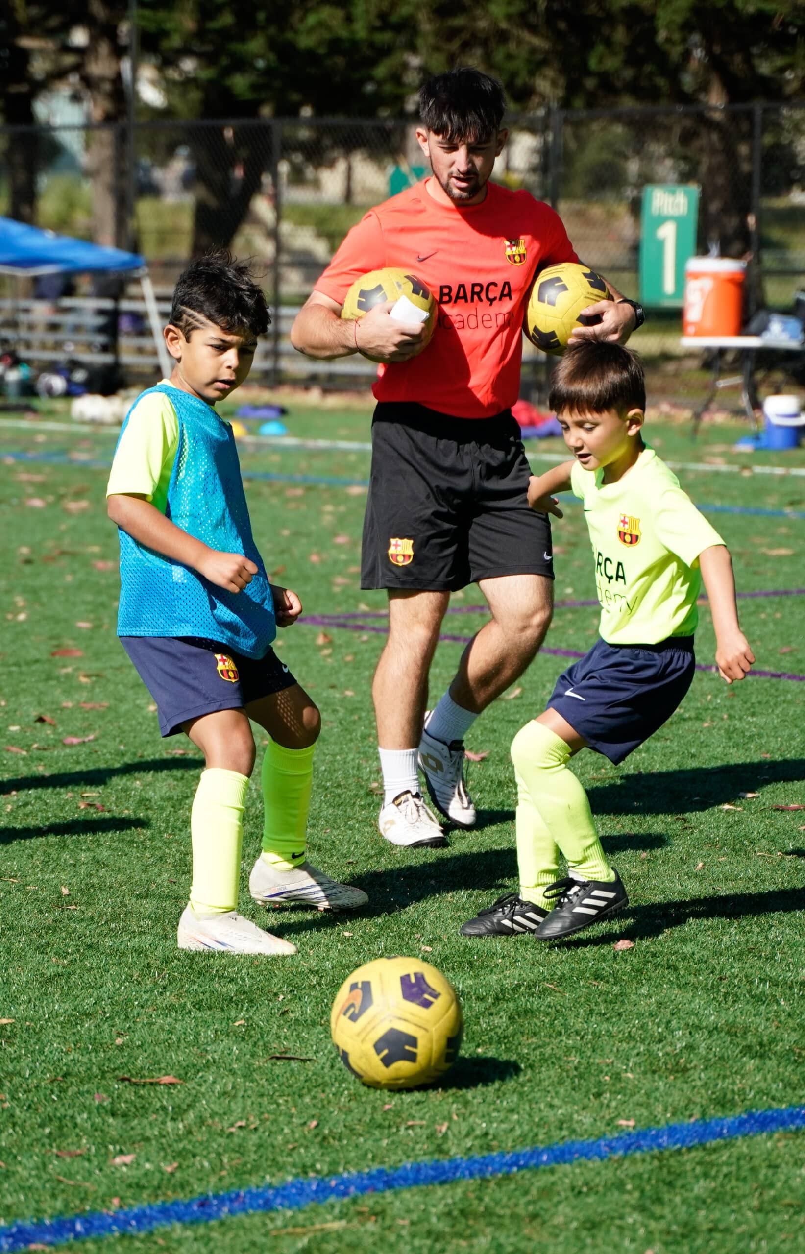 A coach teaching the chip shot in soccer to two kids