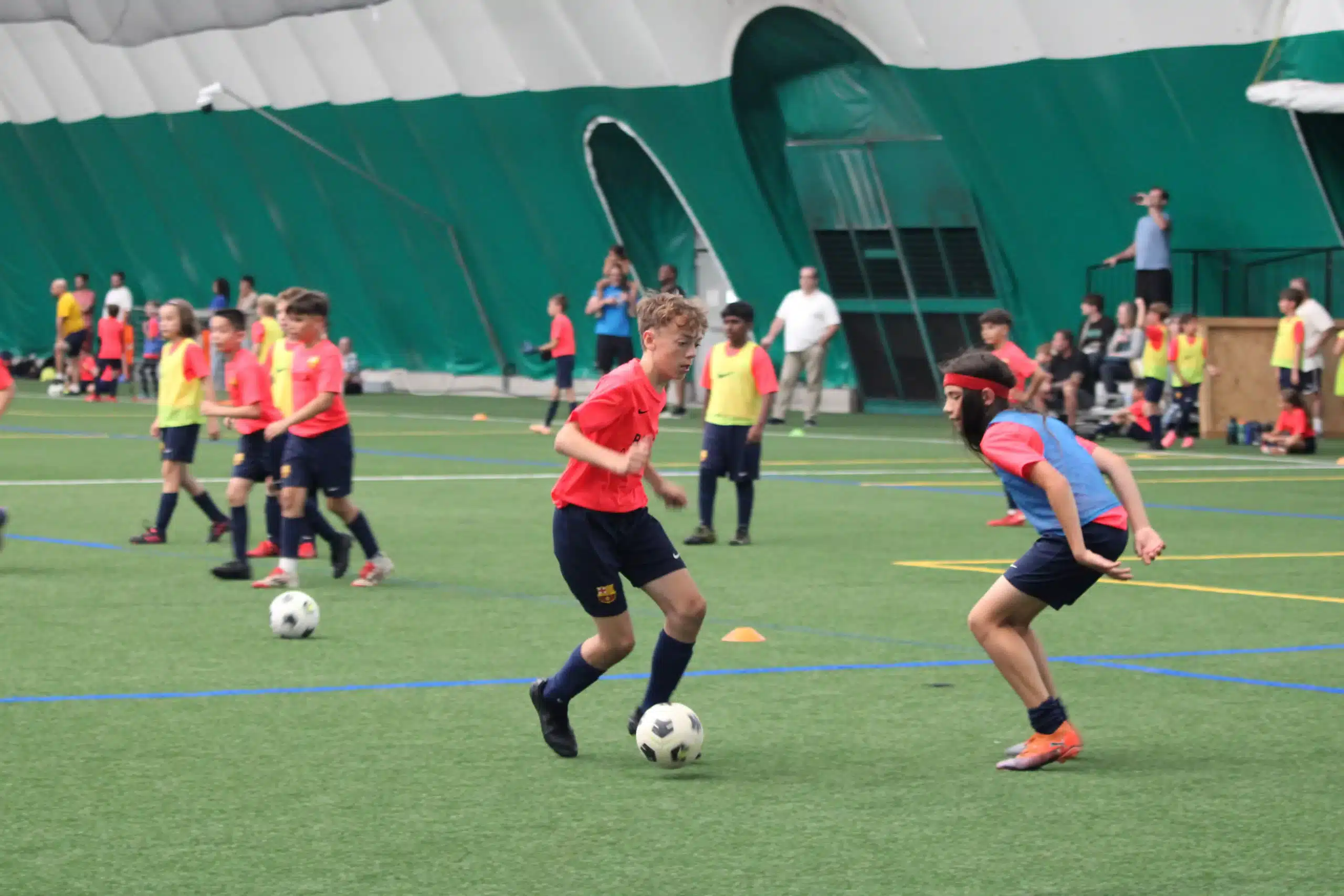 Young players in best soccer cleats for kids maneuvering a ball on artificial grass.